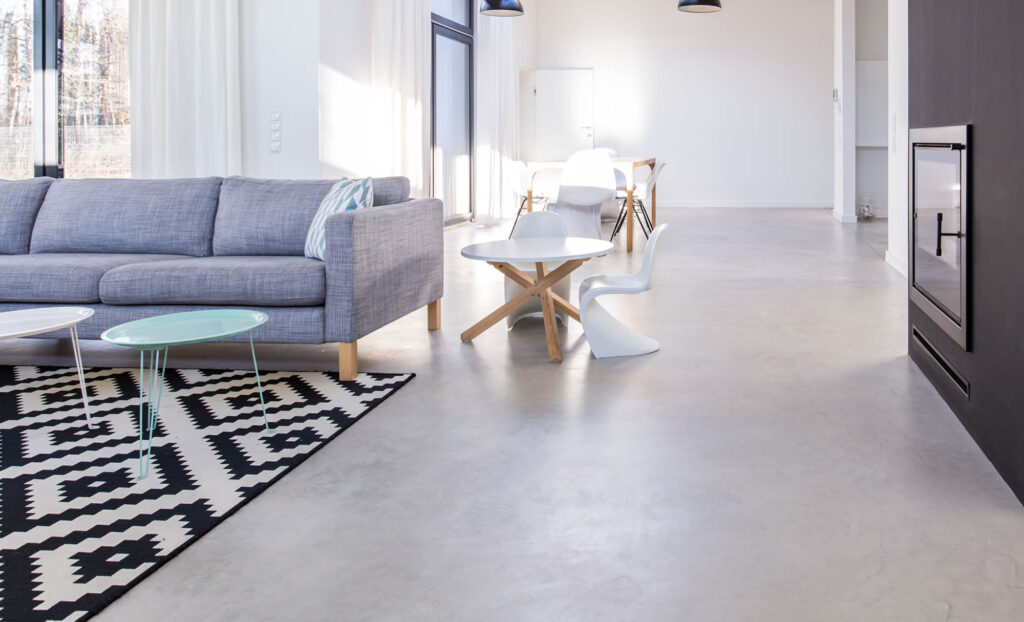 White living room in modern minimalist house with polished concrete floor, fireplace and place for firewood